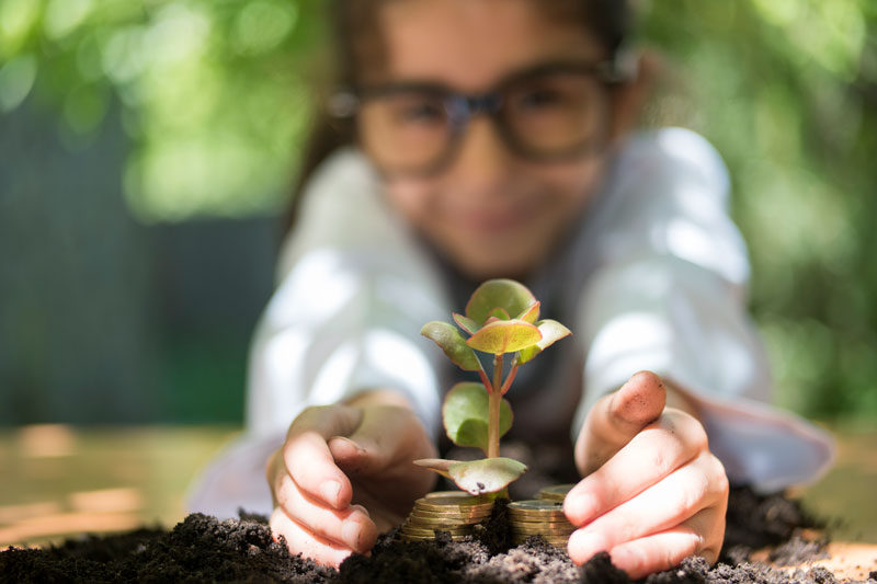girl planting coin under a plant